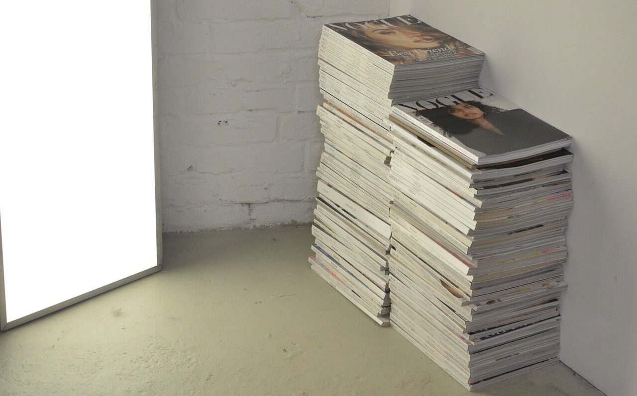 Two piles of Vogue magazines neatly stacked on the floor.